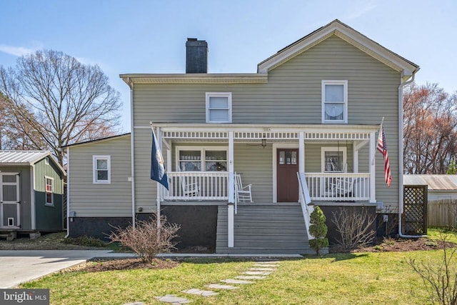 view of front of home featuring a front yard, covered porch, and a chimney