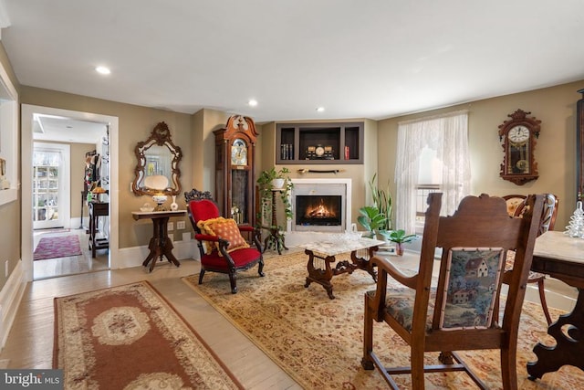 living room with recessed lighting, a lit fireplace, and wood finished floors