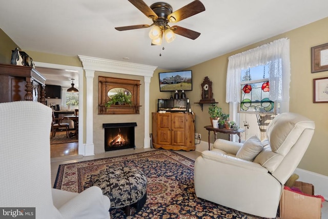 living area featuring a fireplace and a ceiling fan