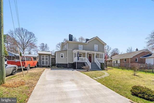 view of front of house featuring an outbuilding, fence, a shed, a porch, and a chimney