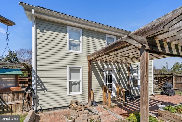 rear view of house featuring entry steps, a pergola, and fence