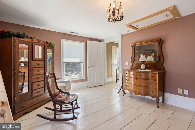 living area featuring visible vents, light wood-style flooring, an inviting chandelier, and baseboards