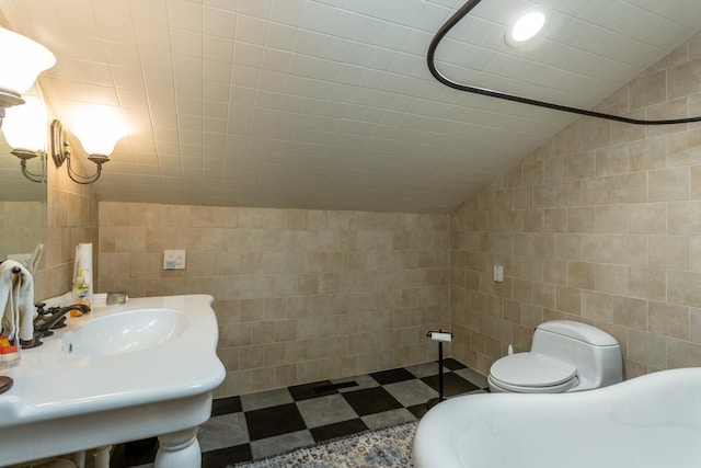 bathroom with vaulted ceiling, sink, tile walls, and toilet