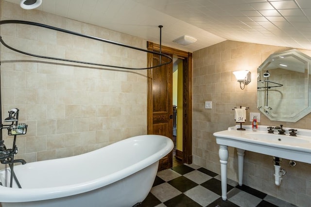 bathroom with tile walls, sink, vaulted ceiling, and a bathing tub