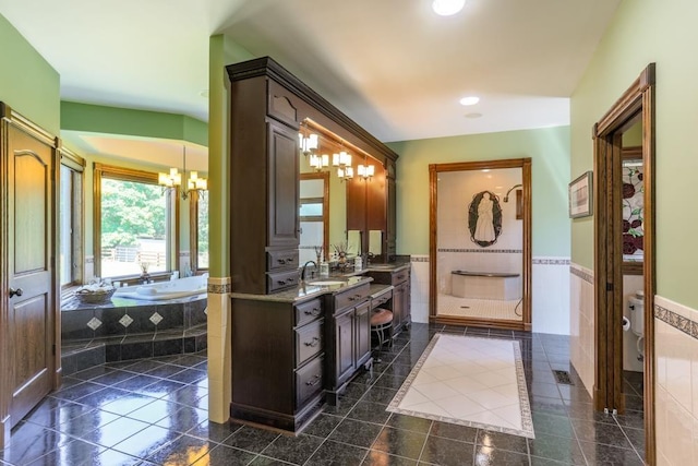 full bathroom with an inviting chandelier, tile walls, vanity, shower with separate bathtub, and toilet