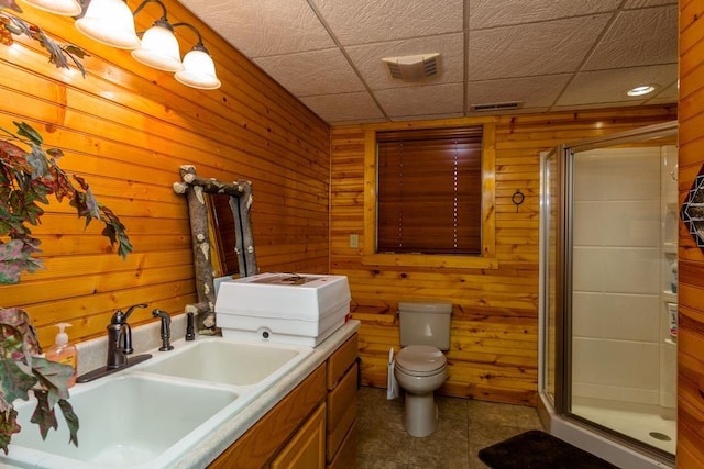 bathroom featuring sink, wooden walls, an enclosed shower, tile patterned floors, and toilet