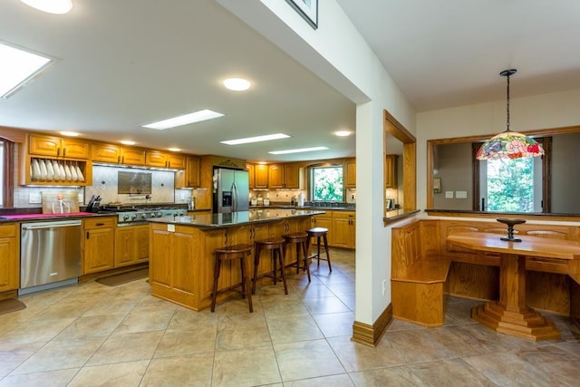 kitchen with stainless steel appliances, a wealth of natural light, a center island, and a breakfast bar area