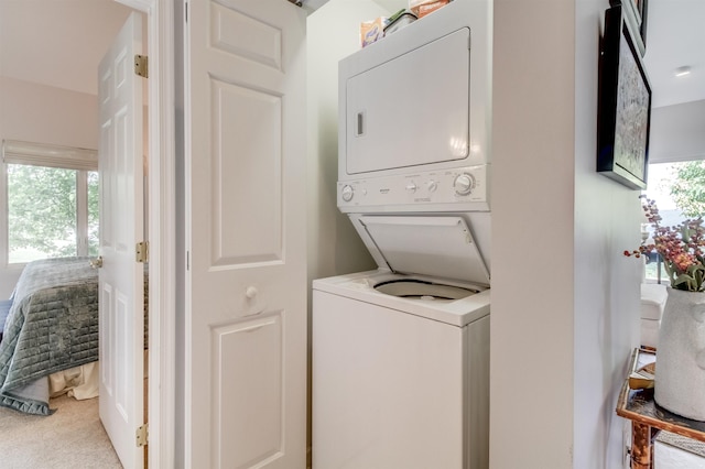 laundry area with stacked washing maching and dryer, carpet floors, and a wealth of natural light