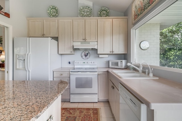 kitchen with lofted ceiling, sink, light tile patterned floors, white appliances, and cream cabinets