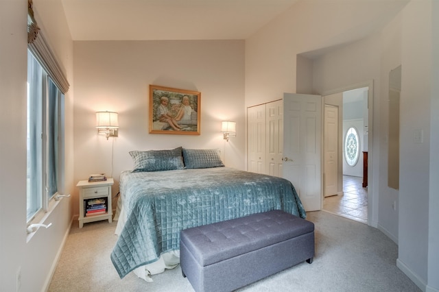 bedroom featuring light carpet, multiple windows, high vaulted ceiling, and a closet