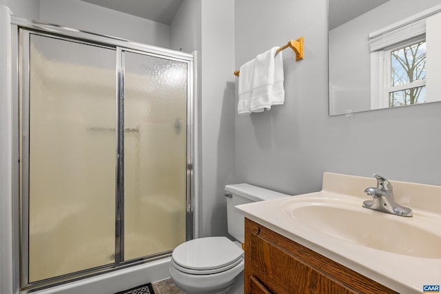 bathroom with a stall shower, toilet, and vanity