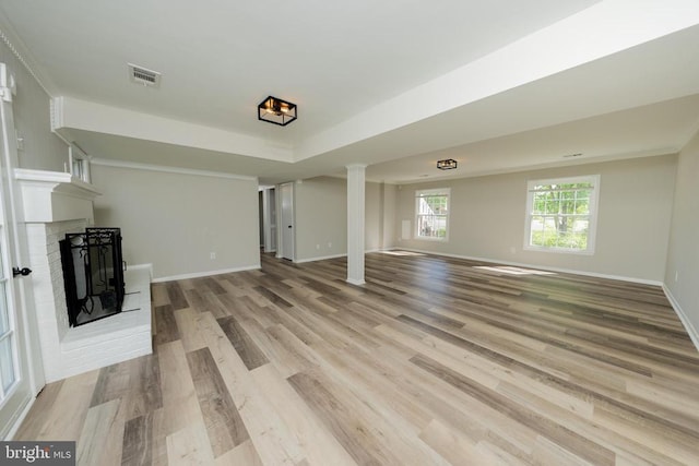 unfurnished living room with a brick fireplace, baseboards, visible vents, and light wood finished floors