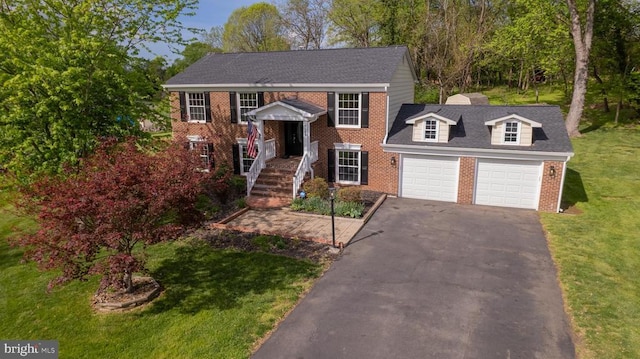 view of front of property featuring brick siding, a garage, driveway, and a front lawn