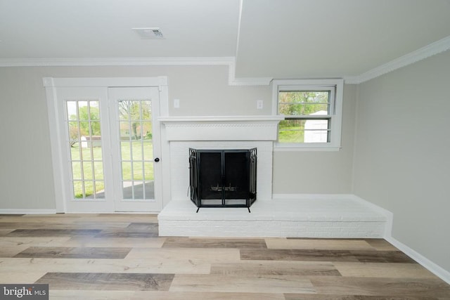unfurnished living room with a fireplace, baseboards, wood finished floors, visible vents, and ornamental molding