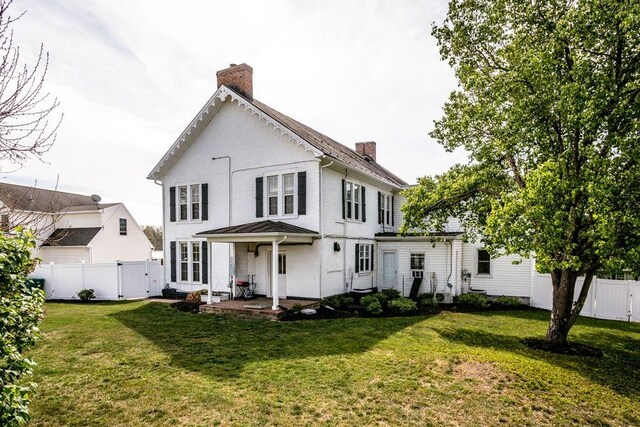 rear view of house with a fenced backyard, a chimney, brick siding, a patio area, and a yard