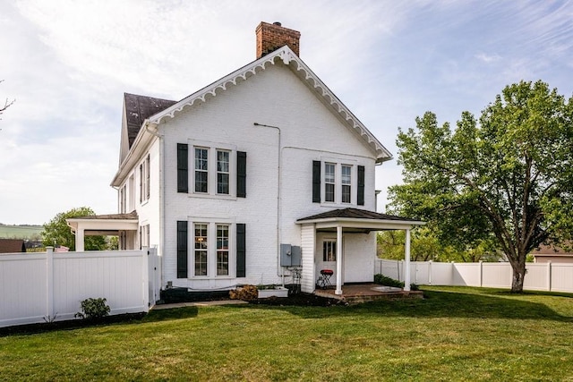 back of house featuring a chimney, a yard, fence private yard, and brick siding