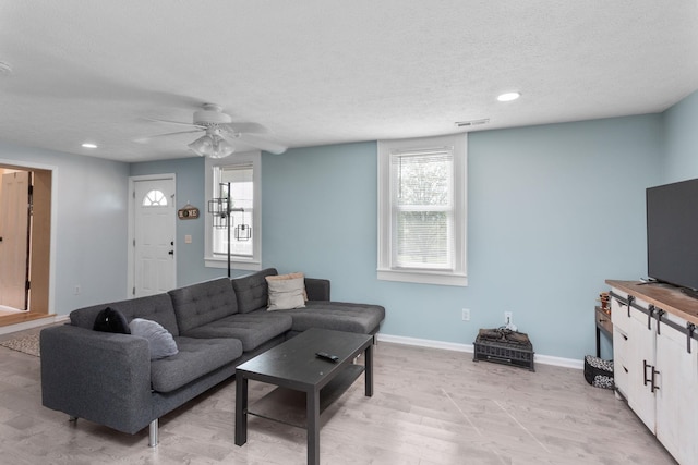living room featuring a textured ceiling, baseboards, plenty of natural light, and ceiling fan