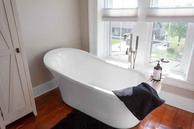 bathroom featuring a freestanding tub, baseboards, and hardwood / wood-style flooring