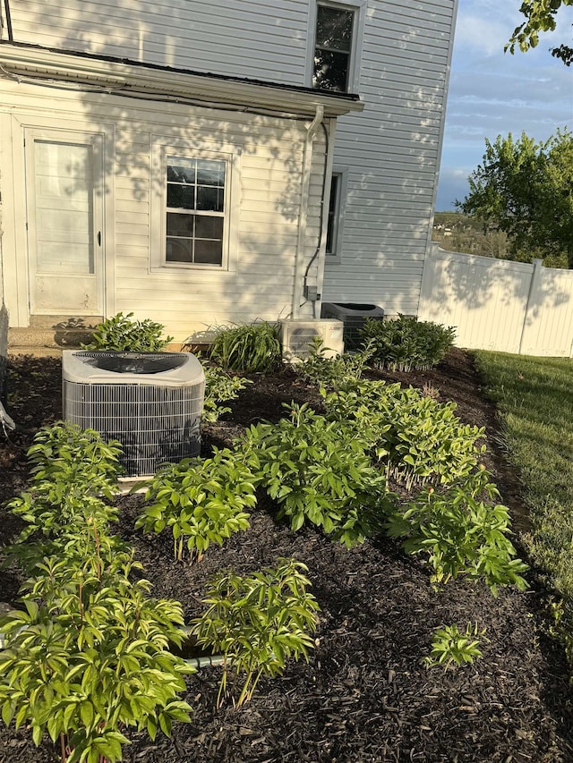 view of side of home with central AC and fence