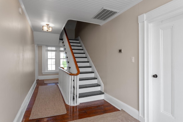 stairway with baseboards, visible vents, and wood finished floors