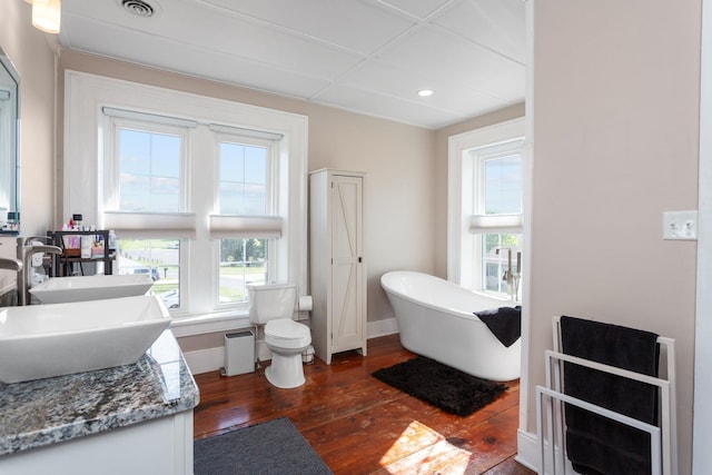 bathroom featuring wood-type flooring, baseboards, plenty of natural light, and a freestanding tub