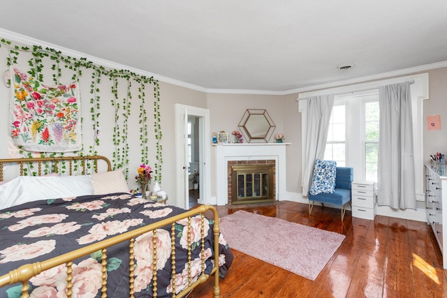 bedroom with crown molding, wood-type flooring, and a brick fireplace