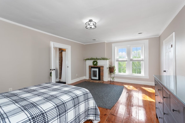 bedroom with crown molding, baseboards, a brick fireplace, and hardwood / wood-style floors