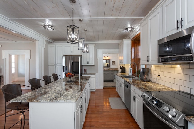 kitchen with a kitchen bar, white cabinetry, tasteful backsplash, a sink, and appliances with stainless steel finishes