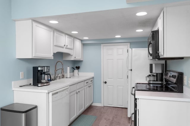 kitchen with white cabinets, white dishwasher, stainless steel range with electric cooktop, black microwave, and a sink