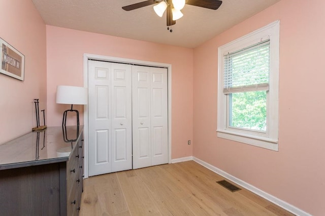 unfurnished bedroom with ceiling fan, baseboards, light wood-type flooring, visible vents, and a closet