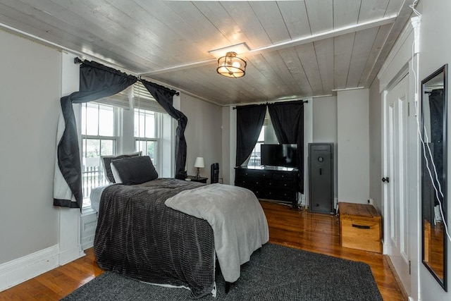 bedroom featuring baseboards, wooden ceiling, wood finished floors, and multiple windows