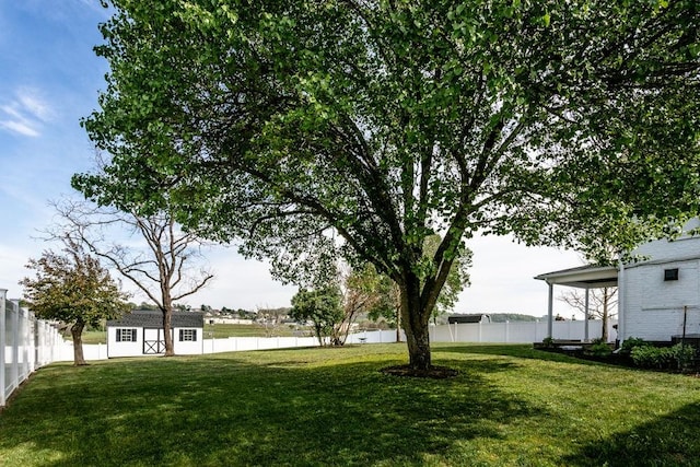 view of yard featuring a water view, an outbuilding, and a fenced backyard