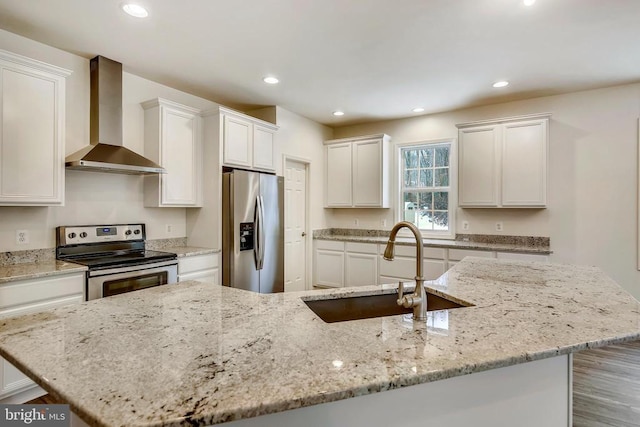 kitchen featuring a sink, stainless steel appliances, wall chimney exhaust hood, and recessed lighting