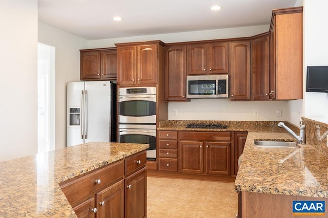 kitchen featuring light tile patterned floors, light stone countertops, recessed lighting, a sink, and stainless steel appliances