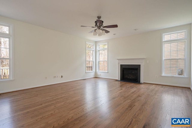 unfurnished living room with a ceiling fan, a fireplace with flush hearth, wood finished floors, and baseboards