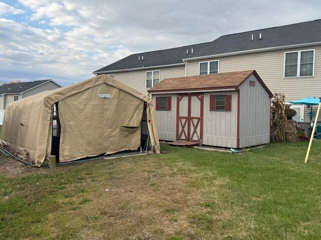 rear view of property with a storage shed and a lawn