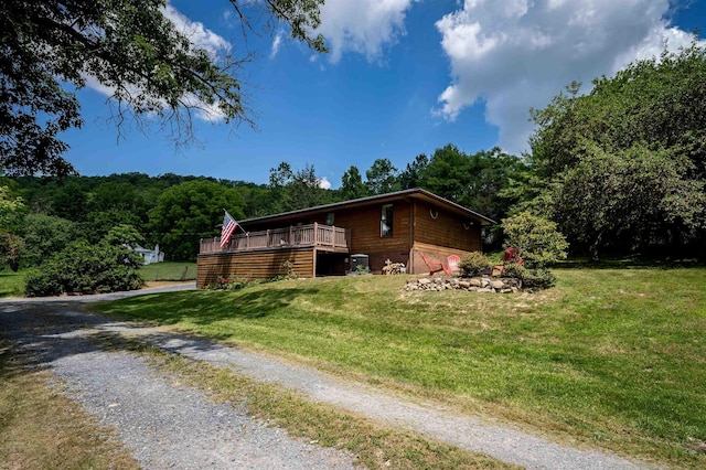 view of side of home with a deck and a lawn