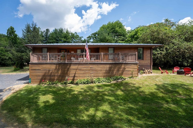 view of front of property featuring a wooden deck, a fire pit, and a front yard