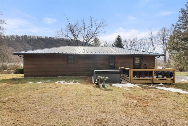 view of side of property featuring a wooden deck, a yard, and a hot tub