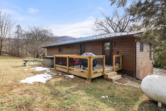 back of property featuring a wooden deck and a lawn