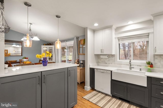 kitchen featuring white dishwasher, sink, decorative light fixtures, and white cabinets