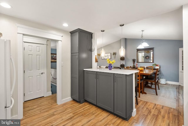 kitchen featuring lofted ceiling, hanging light fixtures, light hardwood / wood-style flooring, white refrigerator, and gray cabinets