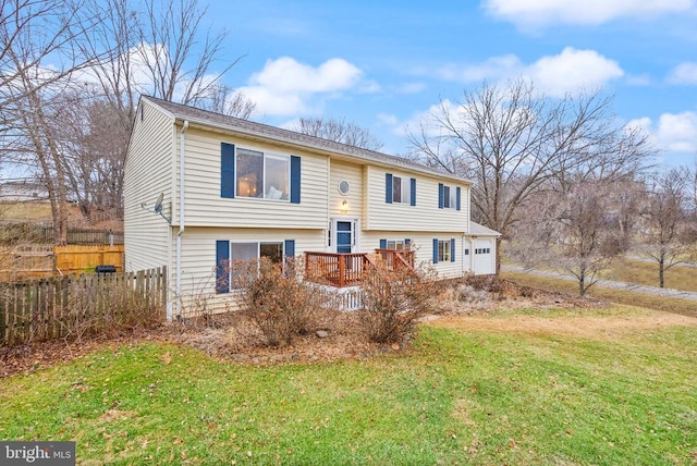 raised ranch featuring a garage, a wooden deck, and a front yard