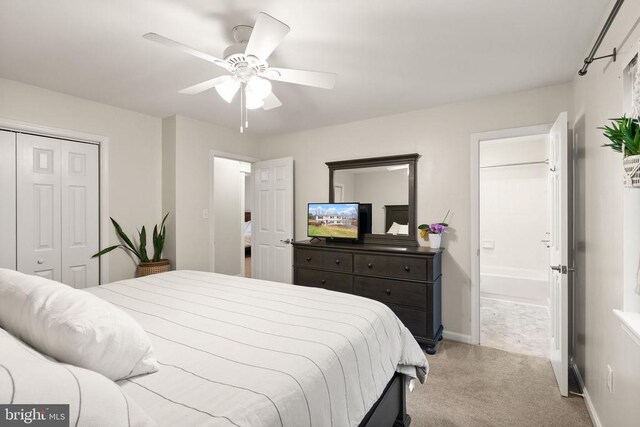 bedroom featuring ceiling fan, a closet, ensuite bathroom, and light carpet