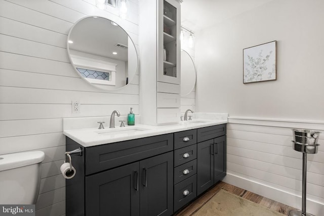 bathroom featuring vanity, hardwood / wood-style floors, wood walls, and toilet