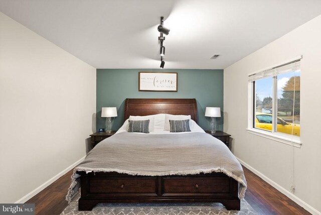 bedroom with dark wood-type flooring and track lighting