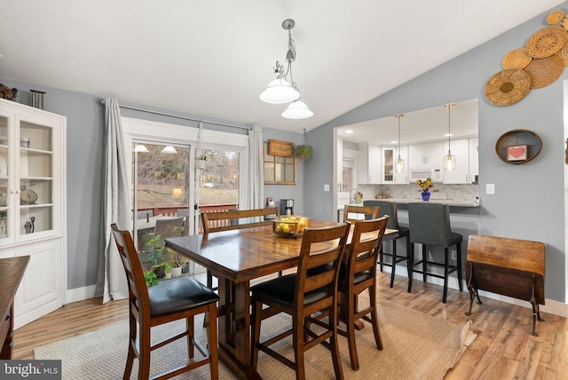 dining space featuring vaulted ceiling and light hardwood / wood-style floors