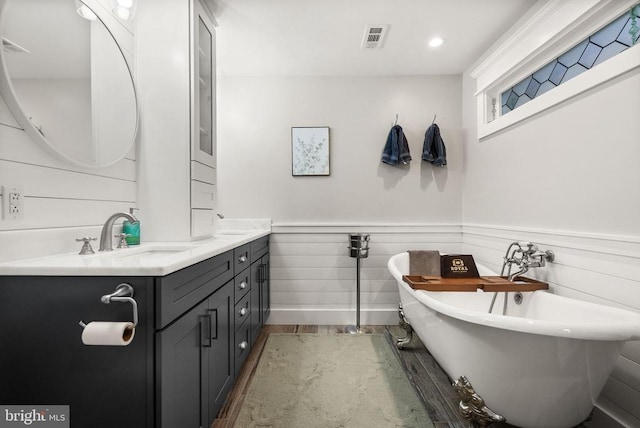 bathroom with a washtub, vanity, and wood-type flooring