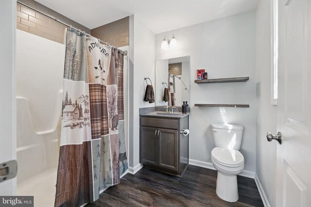 bathroom with vanity, toilet, baseboards, curtained shower, and wood finished floors