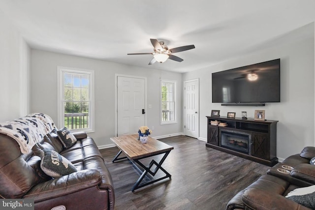 living room with baseboards, dark wood-type flooring, and ceiling fan